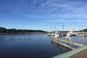 A marina with boats docked, calm water, and a clear sky. - "Under thatched roof" with view of the Bodden lagoon and sauna (Barth)