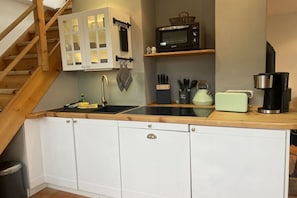 A compact kitchen with a microwave, toaster, and coffee maker on the countertop. - "Under thatched roof" with view of the Bodden lagoon and sauna (Barth)