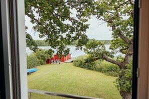A view of a backyard with a lawn, a red shed, and a tree. - Lakefront property, bathing bay (Krakow am See)