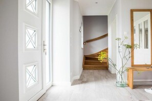 A hallway with white doors, a wooden staircase, and a vase with flowers. - Holiday home with 2 bedrooms (Fuhlendorf)