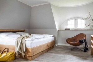 Ein Schlafzimmer mit einem Bett, einem Sessel, einem Fenster und einem kleinen Tisch.