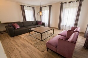 Ein modernes Wohnzimmer mit einer Couch, einem Couchtisch und einer gemütlichen Sitzecke.