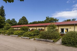 A row of single-story buildings with red roofs, surrounded by dense greenery and a gravel driveway. - on the Baltic Sea - 1 bedroom (Rerik)