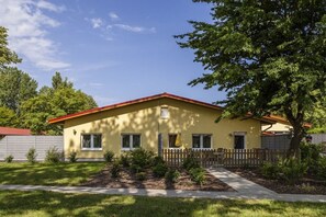 A single-story house with a red roof, a front porch, and a small front yard with a wooden fence. - on the Baltic Sea - 1 bedroom (Rerik)