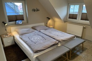 Ein Schlafzimmer mit einem Bett, Nachttischen, einer Bank und einem Fenster.