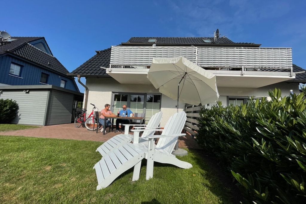 A two-story house with a patio area featuring outdoor seating and a bicycle.