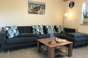 Ein Wohnzimmer mit einer Sofagarnitur, einem Couchtisch und einer Wanduhr.