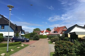 A residential street with houses, a paved driveway, and a parked car. - Holiday apartment with 1 bedroom (Ostseeheilbad Zingst)