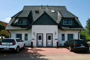 A two-story building with a symmetrical facade, two garage doors, and a tiled roof. - Holiday apartment with 1 bedroom (Ostseeheilbad Zingst)