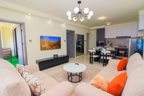 A modern living room with a sofa, a coffee table, and a TV mounted on the wall. - Cozy 2-bedroom apartment in Westlands Nairobi, Kenya (Nairobi)