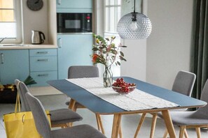 A dining area with a table set for four, a vase with flowers, and a hanging light fixture. - Holiday home with 2 bedrooms (Fuhlendorf)