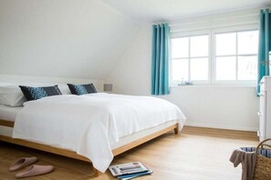 A bedroom with a bed, a window with curtains, a bedside table, and a wall-mounted shelf. - Holiday home with 2 bedrooms (Fuhlendorf)