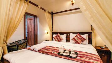 Une chambre d’hôtel avec un lit, des rideaux, une table de chevet, une lampe et un plateau avec un service à thé.
