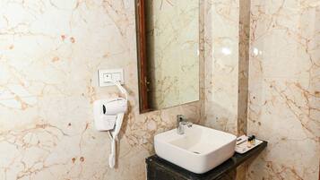 Une salle de bain avec un mur en marbre, un lavabo, un miroir, un porte-serviettes et une poubelle.