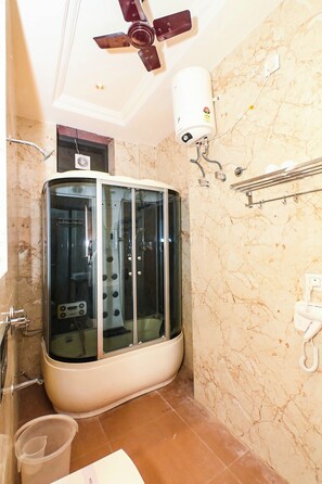 Un baño con ducha acristalada, ventilador de techo y calentador de agua.