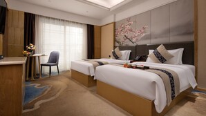 Habitació d'hotel amb dos llits, una taula, una cadira i una finestra gran amb cortines.