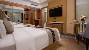 Una habitació d'hotel amb un llit, escriptori, cadira, televisió i mirall.