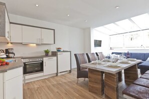 Eine moderne Küche mit weißen Schränken, einem eingebauten Ofen und einem Essbereich mit Holztisch und Stühlen.