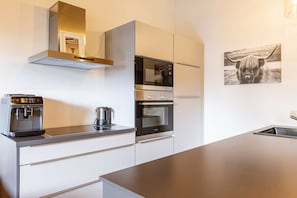 Eine moderne Küche mit Kaffeemaschine, Wasserkocher, Mikrowelle und Backofen.