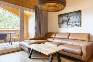 Ein modernes Wohnzimmer mit einer Ledersofa, einem Holztisch und einem großen Fenster mit Blick ins Grüne.