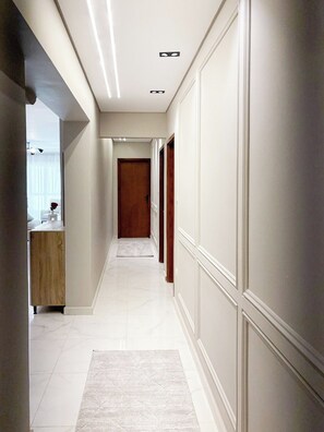 A corridor with a wooden door at the end, white walls, and a marble floor. - 3BRs Magnificent City Center Tranquil Apartment (Cairo Governorate)