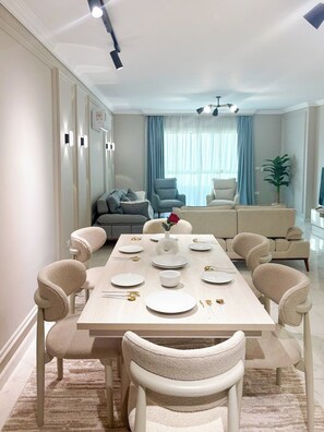 A dining area with a rectangular table set for four, surrounded by upholstered chairs. - 3BRs Magnificent City Center Tranquil Apartment (Cairo Governorate)