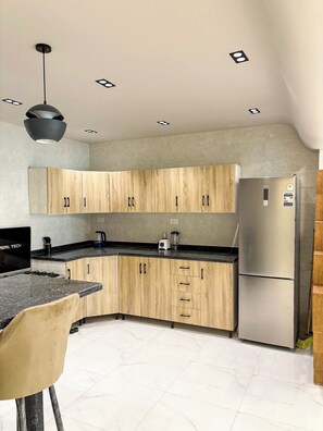 A modern kitchen with wooden cabinets, a stainless steel refrigerator, and a black countertop. - 3BRs Magnificent City Center Tranquil Apartment (Cairo Governorate)