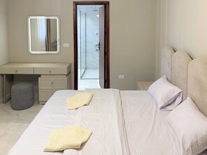 A bedroom with a bed, bedside tables, a mirror, and a bathroom with a shower. - 3BRs Magnificent City Center Tranquil Apartment (Cairo Governorate)