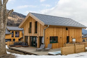 Eine Holzhütte mit einer Terrasse, einem Whirlpool und Bergblick.