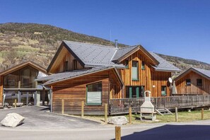 A wooden cabin with a sloped roof, a porch, and a stone fireplace. - Cabin with 1 bedroom (St. Georgen am Kreischberg)