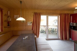 A wooden interior with a dining table, benches, a kitchen area, and a sliding glass door leading outside. - Chalet #12b with IR sauna & whirlpool (St. Georgen am Kreischberg)