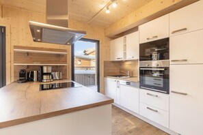 A modern kitchen with wooden cabinetry, stainless steel appliances, and a built-in oven. - Cabin with 1 bedroom (St. Georgen am Kreischberg)