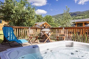 A wooden deck with a hot tub, wooden chairs, and a view of a mountainous landscape. - Cabin with 1 bedroom (St. Georgen am Kreischberg)