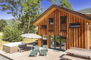 Eine Holzhütte mit Terrasse, Whirlpool und Sitzgelegenheiten im Freien.