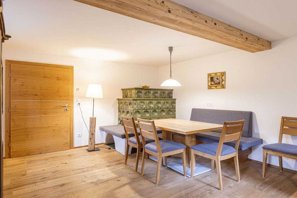 Un comedor con mesa y sillas de madera, un banco, una lámpara y un aparador decorativo.