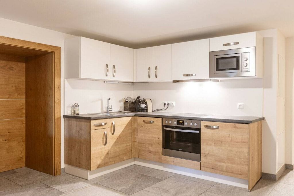 A modern kitchen with wooden cabinets, a built-in oven, and a microwave.