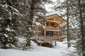 A wooden cabin with a balcony, surrounded by snow-covered trees. - Cabin in Turrach with sauna and balcony (Turrach)