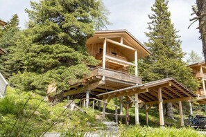 Eine Holzhütte mit einem Balkon, umgeben von Bäumen.