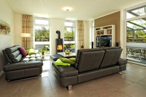 Ein modernes Wohnzimmer mit einer Couch, einem Kamin und einem Essbereich mit Tisch und Stühlen.