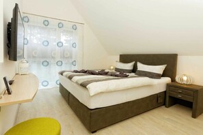 A bedroom with a bed, bedside table, lamp, and a TV mounted on the wall. - Str. d. Freundschaft 30c (Karlshagen)