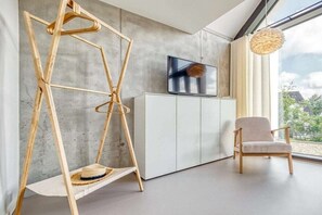 A modern living room with a swing chair, a television, and a view of the outdoors. - Holiday home with 1 bedroom (Fuhlendorf)