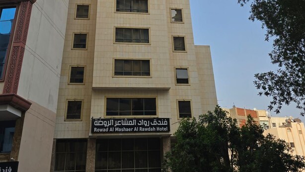 Un edificio de hotel alto con varios pisos y un letrero que indica que es el Rowad Al Mashaer Al Rawdah Hotel.