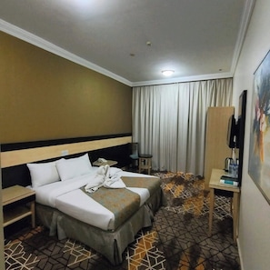 Ein Hotelzimmer mit einem Bett, einem Schreibtisch, einem Sessel, einem Fernseher und einem Bild an der Wand.
