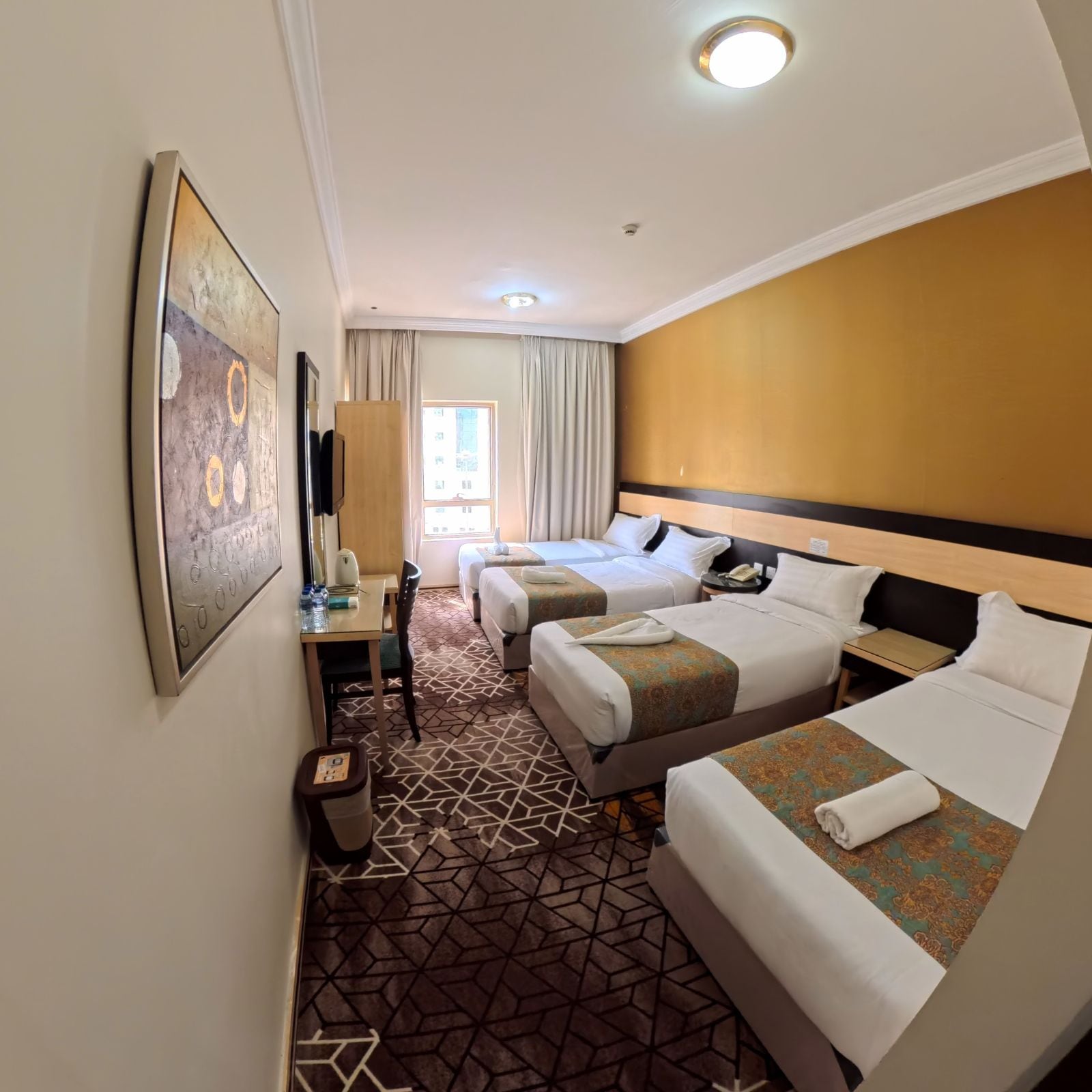 Habitación de hotel con dos camas, un escritorio, una silla, un cesto de basura y una ventana con cortinas.