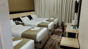 Ein Hotelzimmer mit drei Betten, einem Schreibtisch und einem Spiegel.