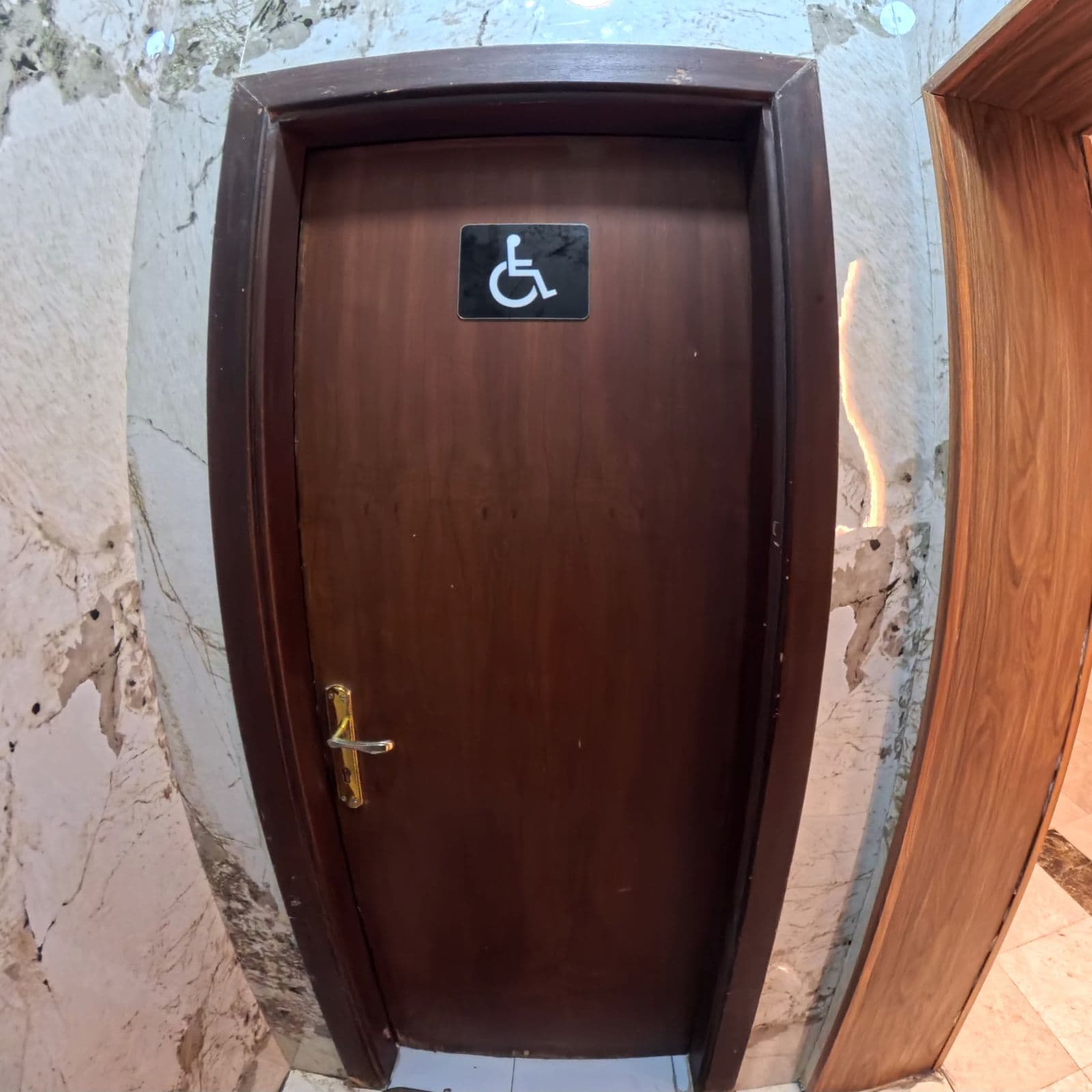 Una puerta de madera con un letrero de accesibilidad para sillas de ruedas.