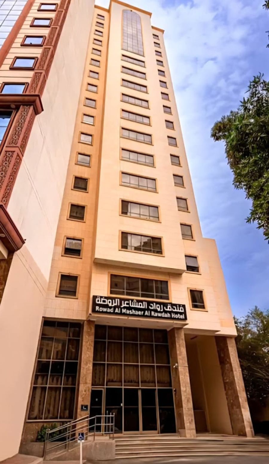 A tall hotel building with a sign in Arabic.