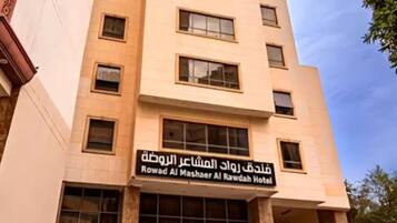 A tall hotel building with a sign in Arabic.
