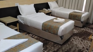 Una habitación de hotel con dos camas, una mesita de noche con teléfono y una alfombra estampada.