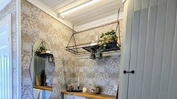 A bathroom with a wooden floor, a mirror, a sink, and a cabinet.
